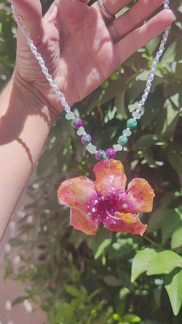 Collar de hibisco naranja rosado real resinado, con cristal facetado y piedra mineral natural en  – joya botánica artesana