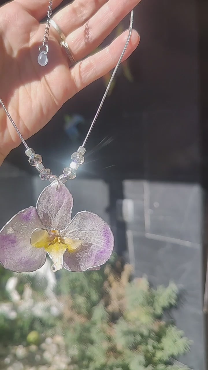 Collar de acero inoxidable hecho a mano con orquídea Phalaenopsis real deshidratada, bordes en nácar lila, resina UV y cuentas de cristal checo