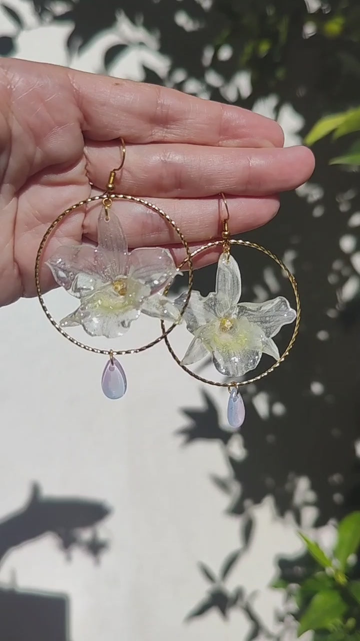 Pendientes con Mini Orquídeas Dendrobium Reales en Resina – Aro Dorado y Lágrimas de Cristal Iridiscente – Joyería Floral Hecha a Mano