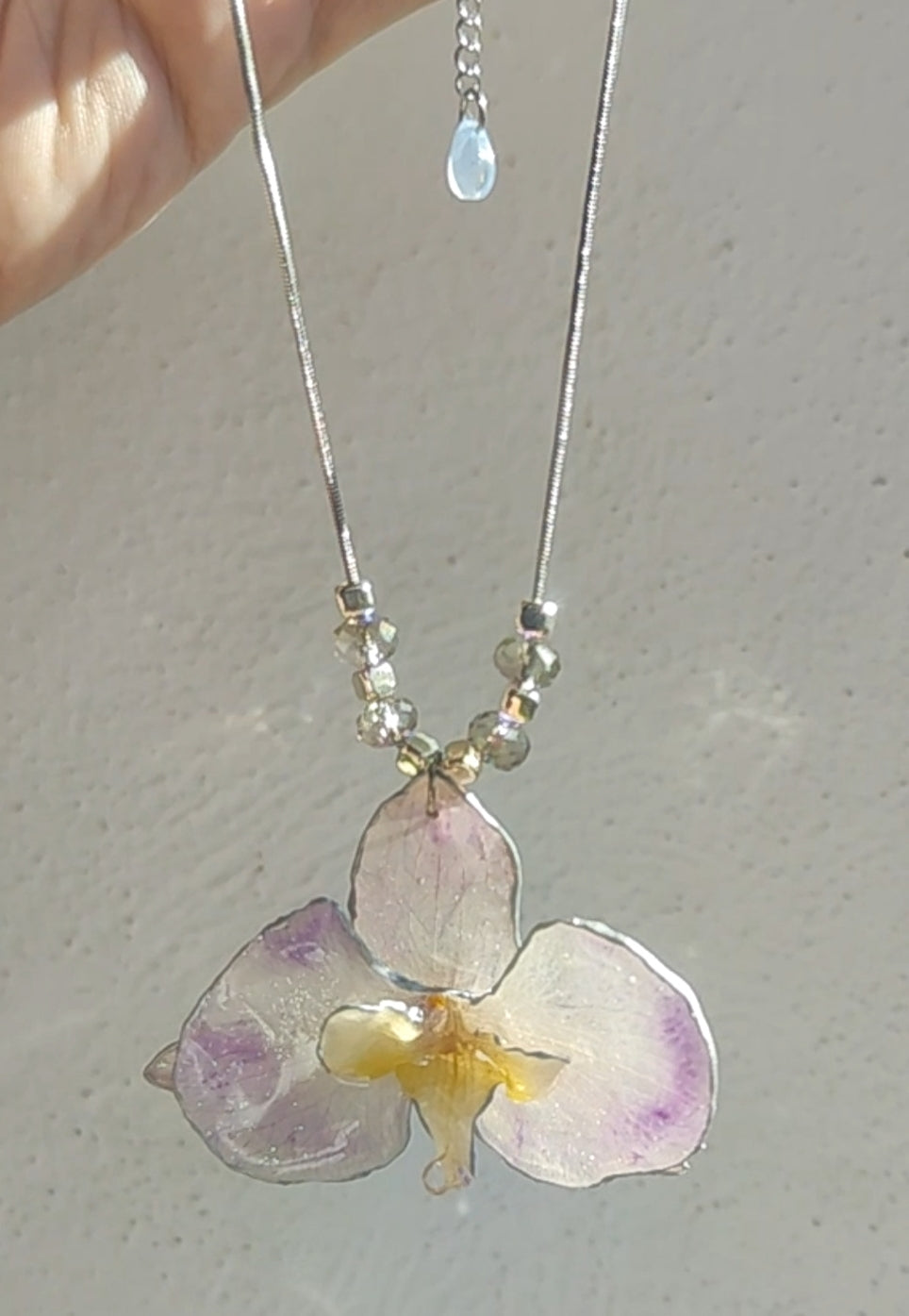 Collar de acero inoxidable hecho a mano con orquídea Phalaenopsis real deshidratada, bordes en nácar lila, resina UV y cuentas de cristal checo